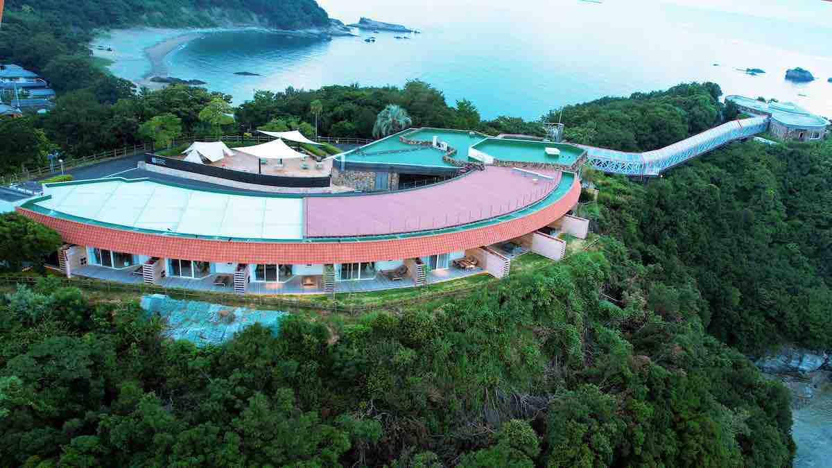 手前の建物が「小松島リゾート」の宿泊棟。ガラス張りの渡り廊下の先には海一望のレストラン「ペティ イゾラ」がある