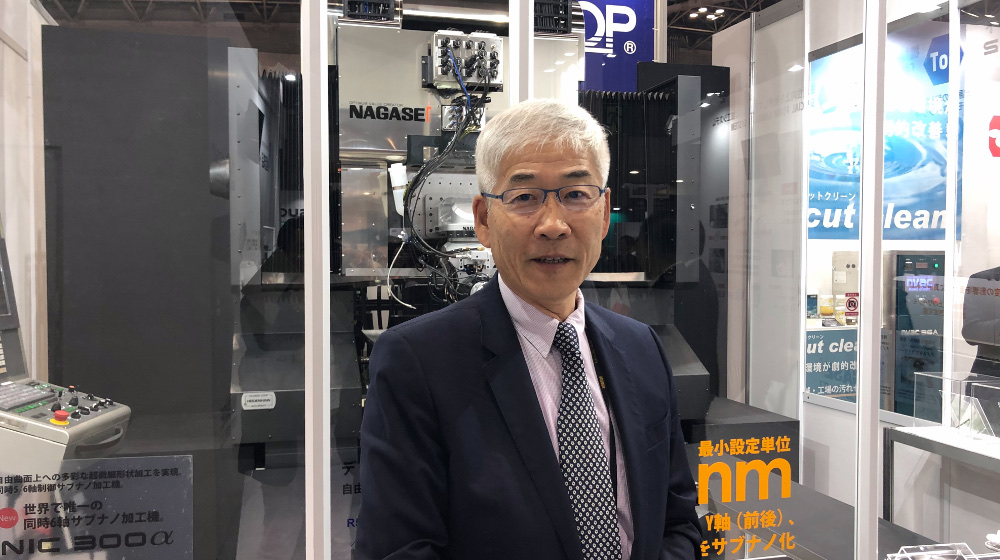 ナガセ インテグレックス代表取締役社長の長瀬幸泰氏。創業は1950年。後ろは同社自慢の超精密加工機