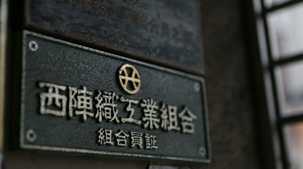 西陣岡本の玄関に掲げられた、西陣織工業組合の組合員証。歴史を物語る風合いがある