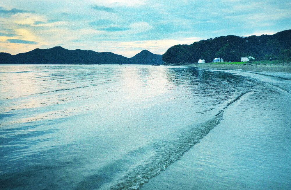 朝の光の中、裸足で穏やかな波が寄せる浜を歩く気持ちよさ